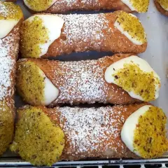 Chrupiące rurki wypełnione kremem, posypane cukrem pudrem i pistacjami. Pyszne **cannoli** czekają!