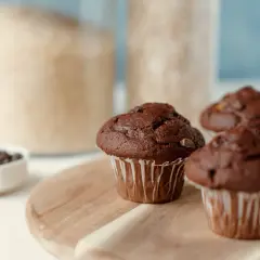 Puszyste muffinki czekoladowe, idealne na każdy przepis. W tle słoiki z cukrem i mąką.