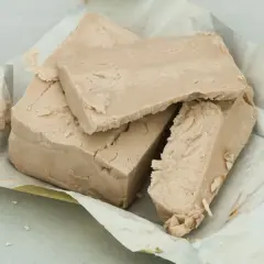 Kostki świeżych drożdży, które można mrozić, rozpakowane na papierze.