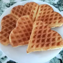 Sześć złotych gofrów w kształcie serca na białym talerzu. Idealne na najprostszy przepis na gofry.