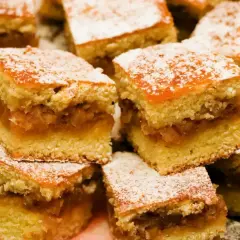 Pulchny jabłecznik z dawnych lat, pokrojony w kostkę i posypany cukrem pudrem. Smak dzieciństwa na talerzu.