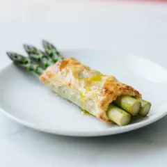 Chrupiące ciasto francuskie w airfryerze otula pędy zielonych szparagów, skropione oliwą. Pyszna przekąska gotowa w mgnieniu oka!