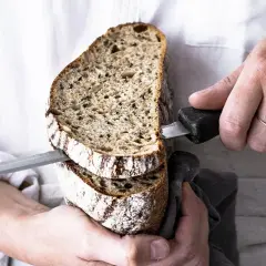 Krojony bochenek chleba na zakwasie, idealny do przepisu. Dwie kromki z widocznym wnętrzem i chrupiącą skórką.
