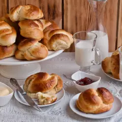 Złociste bułki brioche, mleko i dżem czekają na śniadanie. Idealne na rodzinny poranek.
