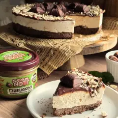 Pyszne ciasto kinder bueno z mascarpone, udekorowane czekoladą i orzechami. Obok słoik pasty z orzechów laskowych.