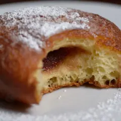 Puszysty pączek z dżemem, posypany cukrem pudrem, jak z babcinego, starego przepisu na pączki.