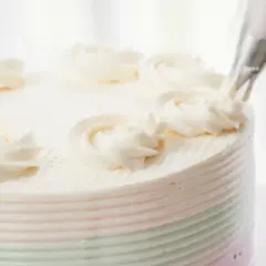 Krem do tortu jak dawniej, dekorowany ręcznie. Delikatne różyczki z kremu zdobią biały tort, przywołując smak tradycji.