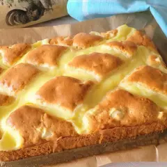 Wilgotne ciasto jogurtowe z budyniem, pieczone na papierze, z ozdobnym wałkiem w tle.