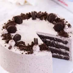 Pyszny tort z masą oreo, udekorowany pokruszonymi ciastkami i całymi ciasteczkami.