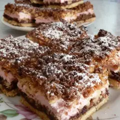 Pyszny pleśniak przepis babci, z kremową różową masą i kruszonką, posypany cukrem pudrem.