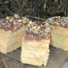 Sernik gotowany przepisy babci – pyszne, warstwowe ciasto z kremem, polane czekoladą i posypane orzechami.