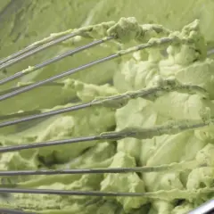 Mieszadła miksera pokryte kremem pistacjowym z mascarpone. Zielona, puszysta masa w misie.