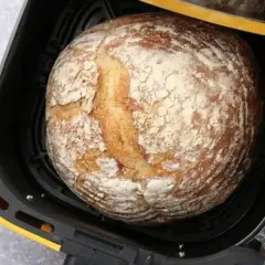 Chleb z airfryer, rumiany i posypany mąką, czeka na wyjęcie.