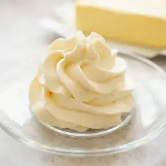 Krem patissiere w kształcie róży na talerzyku, w tle kostka masła.