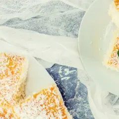 Pyszne ciasto kokosowe, posypane wiórkami, prezentuje się apetycznie na białych talerzach. Idealne na deser!