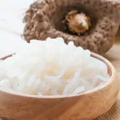 Miska pełna białego makaronu z mąki konjac, obok bulwa tej rośliny.
