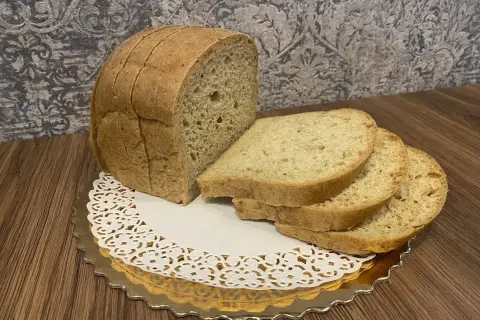 Chleb keto, pokrojony w kromki, prezentuje się apetycznie na złotym talerzyku. Idealny na dietę niskowęglowodanową.