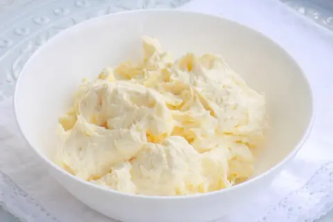 Puszysta masa budyniowa z mascarpone w białej misce, gotowa do użycia w deserach.