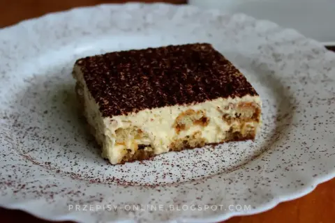 Pyszne tiramisu, czyli zabajone, na białym talerzu, posypane kakao.