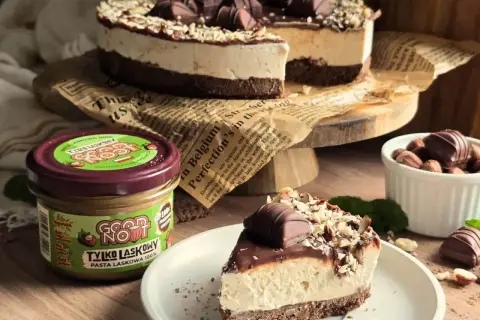 Pyszne ciasto kinder bueno z mascarpone, udekorowane czekoladą i orzechami. Obok słoik pasty z orzechów laskowych.