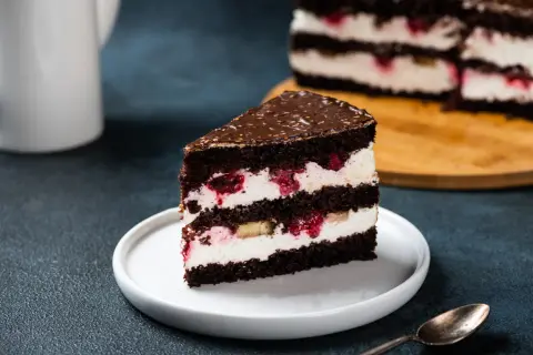 Obłędny tort czekoladowy z mascarpone i owocami, z malinami i bananami, polany czekoladą.