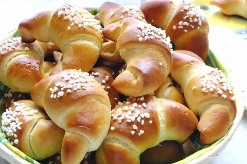 Koszyk pełen mięciutkich rogalików drożdżowych, posypanych cukrem. Idealne na śniadanie, zgodnie z przepisem na pyszne wypieki.
