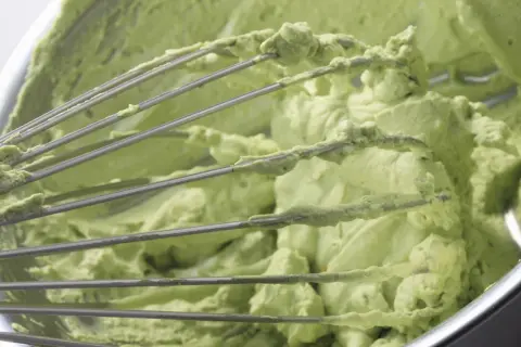Mieszadła miksera pokryte kremem pistacjowym z mascarpone. Zielona, puszysta masa w misie.
