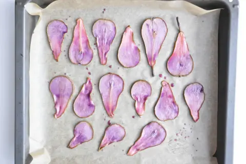 Karmelizowana gruszka w fioletowym odcieniu, ułożona na papierze do pieczenia.