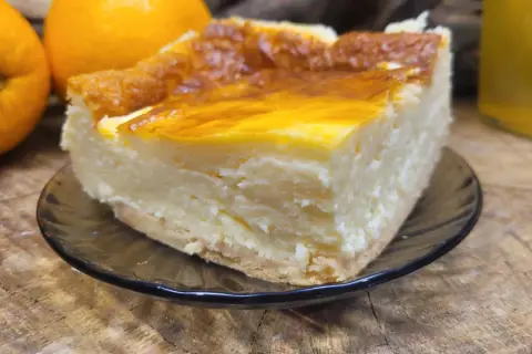 Kawałek sernika na talerzyku, obok pomarańcze. Może to najstarszy przepis na sernik?