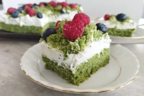 Zielone ciasto leśny mech na dużą blachę, przełożone kremem z serkiem mascarpone, ozdobione malinami i borówkami.