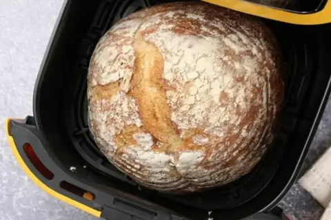 Chleb z airfryer, rumiany i posypany mąką, czeka na wyjęcie.