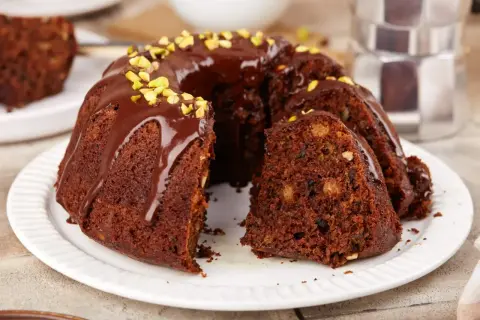 Pyszna, wilgotna babka czekoladowa z bakaliami, polana polewą i posypana pistacjami. Idealna na deser.