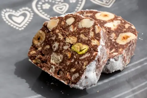 Dwa kawałki czekoladowego przysmaku z orzechami i pistacjami, przypominające blok czekoladowy przepis babci.