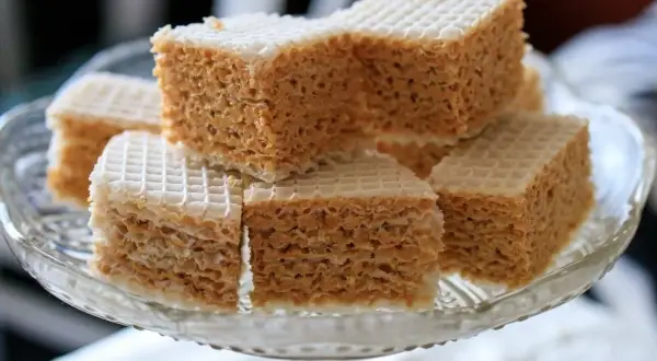 Słodkie wafle przekładane kremem z mleka w proszku, ułożone na szklanej paterze.