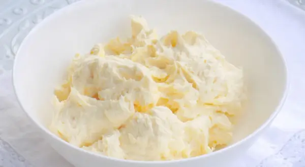Puszysta masa budyniowa z mascarpone w białej misce, gotowa do użycia w deserach.