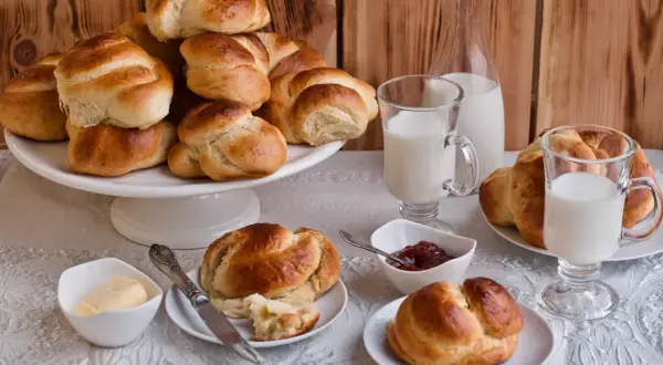 Złociste bułki brioche, mleko i dżem czekają na śniadanie. Idealne na rodzinny poranek.