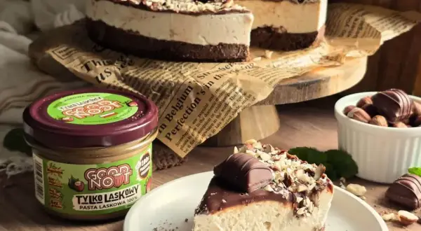 Pyszne ciasto kinder bueno z mascarpone, udekorowane czekoladą i orzechami. Obok słoik pasty z orzechów laskowych.