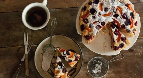 Pyszne ciasto bez glutenu z owocami, posypane cukrem pudrem. Idealne na podwieczorek z herbatą.