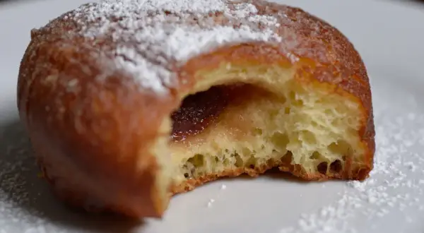 Puszysty pączek z dżemem, posypany cukrem pudrem, jak z babcinego, starego przepisu na pączki.