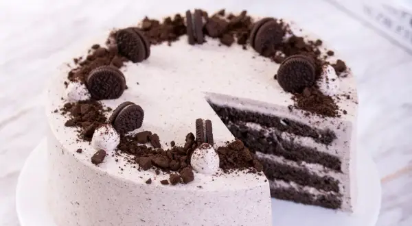Pyszny tort z masą oreo, udekorowany pokruszonymi ciastkami i całymi ciasteczkami.