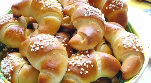 Koszyk pełen mięciutkich rogalików drożdżowych, posypanych cukrem. Idealne na śniadanie, zgodnie z przepisem na pyszne wypieki.