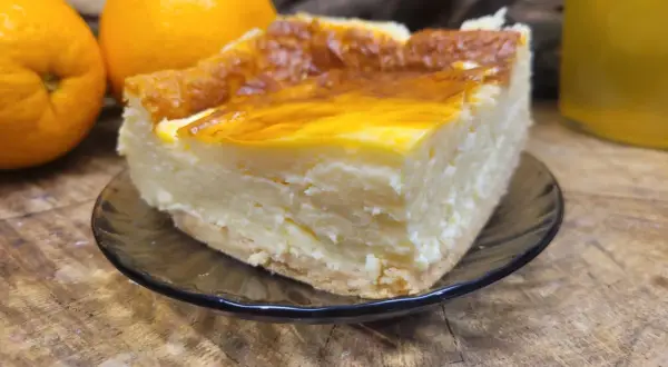 Kawałek sernika na talerzyku, obok pomarańcze. Może to najstarszy przepis na sernik?