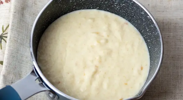 Kremowy sos z mascarpone w rondelku, gotowy do podania z deserem.
