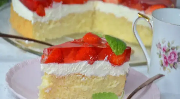 Puszysty biszkopt z truskawkami i mascarpone, oblany galaretką. Idealny deser na letnie popołudnie.