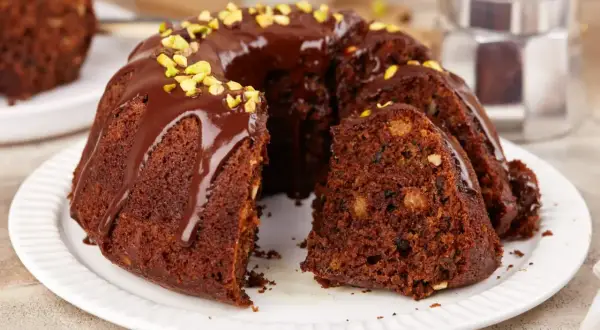 Pyszna, wilgotna babka czekoladowa z bakaliami, polana polewą i posypana pistacjami. Idealna na deser.