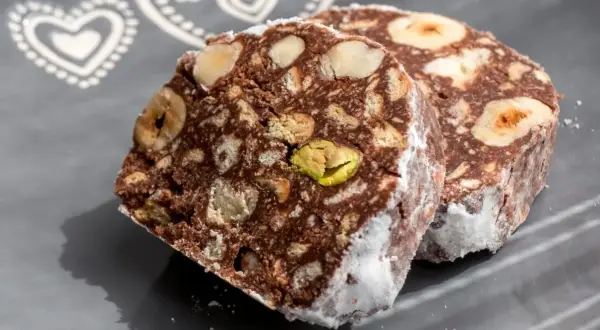 Dwa kawałki czekoladowego przysmaku z orzechami i pistacjami, przypominające blok czekoladowy przepis babci.