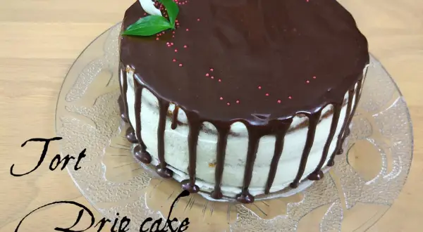 Pyszny tort drip cake z polewą czekoladową i różową posypką, ozdobiony listkami.
