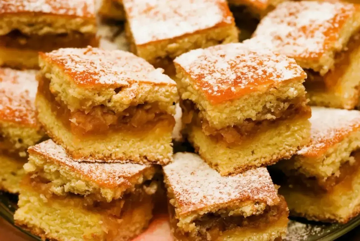 Pulchny jabłecznik z dawnych lat, pokrojony w kostkę i posypany cukrem pudrem. Smak dzieciństwa na talerzu.