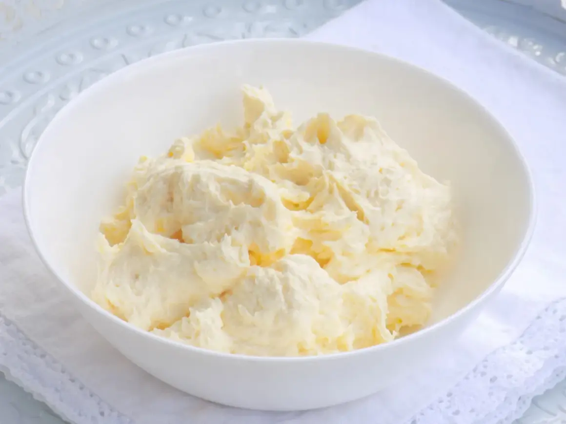 Puszysta masa budyniowa z mascarpone w białej misce, gotowa do użycia w deserach.