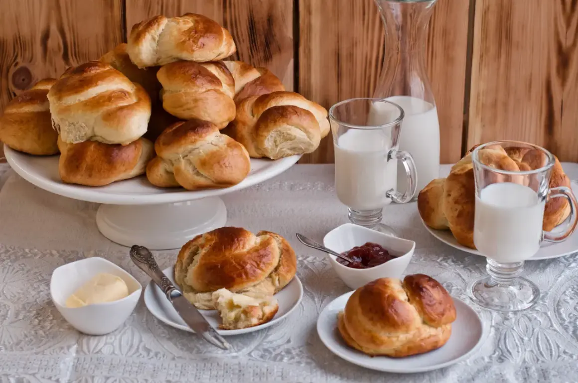 Złociste bułki brioche, mleko i dżem czekają na śniadanie. Idealne na rodzinny poranek.